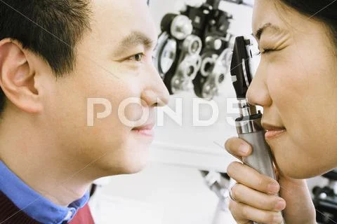 Asian female optometrist examining patient Stock Photos