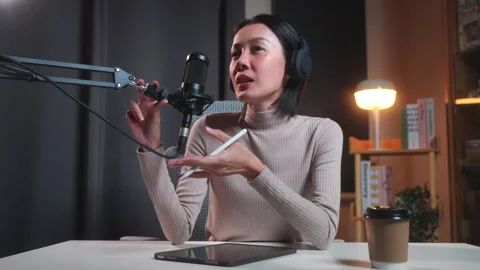 Asian female podcaster wth tablet in a modern home studio Stock Footage 345046375