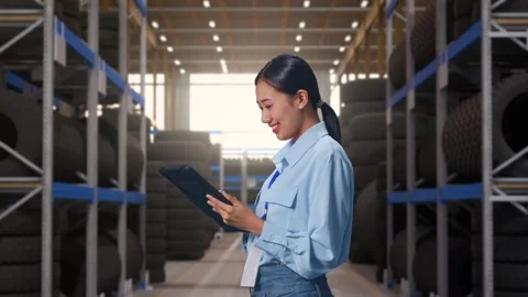 Asian Female Professional Worker Focused On Her Tablet at Tire Warehouse Stock Footage 341786053