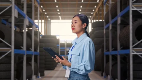 Asian Female Professional Worker Use Tablet And Look Around at Tire Warehouse Stock Footage 341786050
