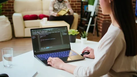 Asian female programmer works on coding software in a home office setup Video stock 319713343