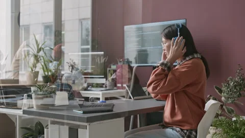 Asian Female Software Developer Enjoying Music while Working on Laptop Stock Footage 285712727