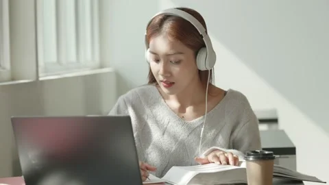 Asian Female student taking notes from a book at library. Young asian woman sitt Stock Footage 220895111