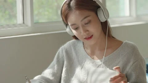 Asian Female student taking notes from a book at library. Young asian woman sitt Stock Footage 220895196