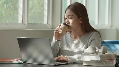 Asian Female student taking notes from a book at library. Young asian woman sitt Stock Footage 220896155