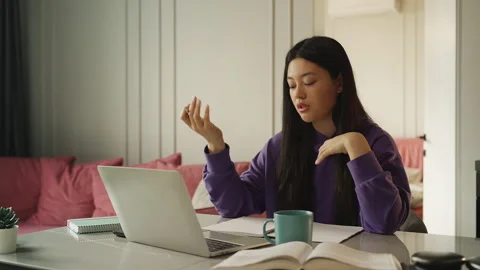 Asian female student taking notes during an online video lesson on a laptop Stock Footage 337949974