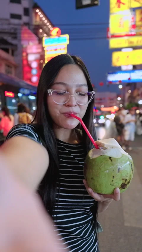 Asian female takes a selfie while drinking coconut at street food in Thailand. Video stock 342483414