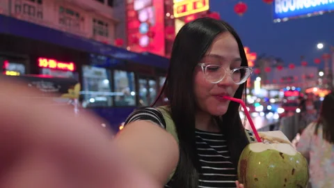 Asian female takes a selfie while drinking coconut at street food in Thailand. Video stock 342483458