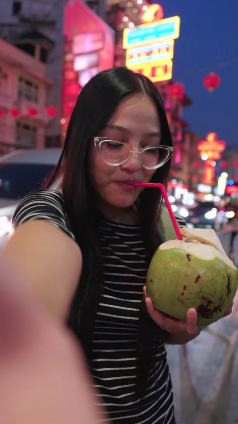Asian female takes a selfie while drinking coconut at street food in Thailand. Video stock 342483510