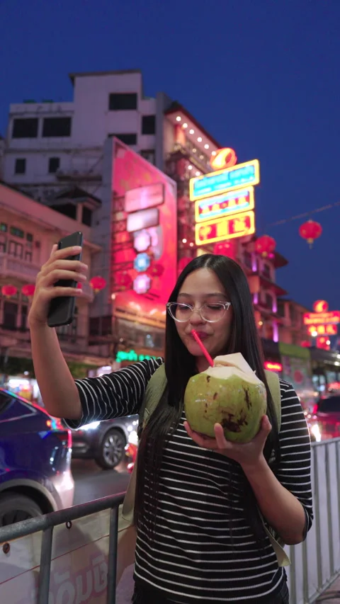 Asian female takes a selfie while drinking coconut at street food in Thailand. Video stock 342483546