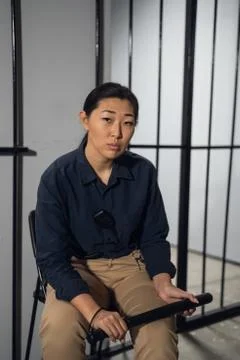 Asian female taskmaster sits in the background of cells with prisoners in a Stock Photos
