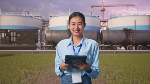 Asian Female Worker Use Tablet And Smiling To Camera at Oil Refinery Stock Footage 340139389
