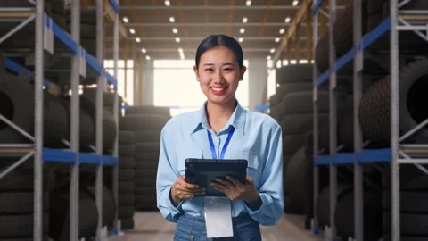 Asian Female Worker Use Tablet And Smiling To Camera at Tire Warehouse Stock Footage 341786024