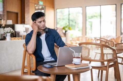 Asian freelancer man thinking deep in thought while working on laptop at ta.. Stock Photos