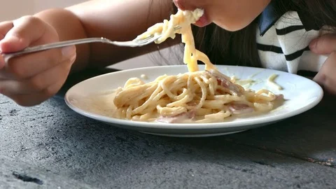 Asian girl with fork in hands eats pasta, close-up 스톡 동영상 74653507