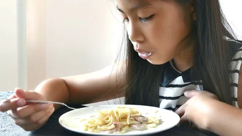 Asian girl with fork in hands eats pasta, close-up 스톡 동영상 74653560