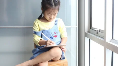 Asian girl funny with tablet computer sitting on wood chair in living room Stock Footage 97435865