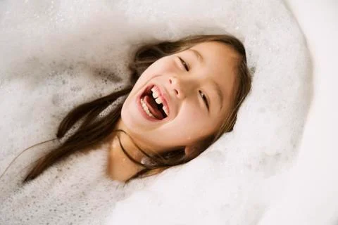 Asian girl laughing in bubble bath Stock Photos