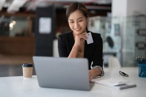 Asian girl making online payment using laptop and credit card for shopping at Stock Photos