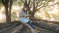 Asian Girl Reading A Book While Sitting Under A Tree In The Park. Stock Footage