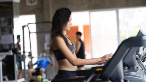 Asian girl running on the treadmill in the gym Stock Footage