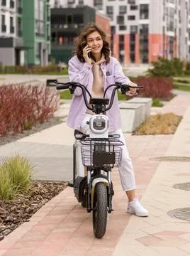 Asian girl using phone while sitting on electric scooter Stock Photos