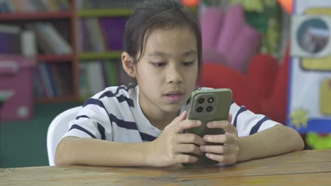 Asian girl using a smartphone for mobile learning and educational apps at home Stock Footage 335881493