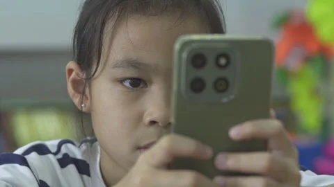 Asian girl using a smartphone for mobile learning and educational apps at home Stock Footage 335882295