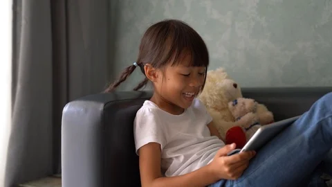 Asian girl Using tablet , watching cartoon, playing games on sofa Stock Footage 110780202