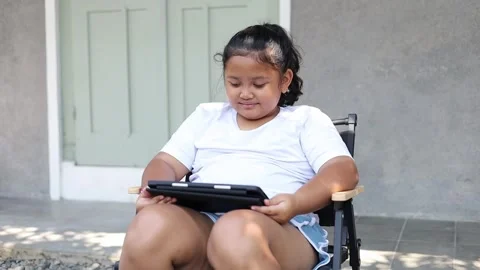 Asian girl using a tablet while sitting outdoors at home, representing digital Stock Footage 340839065