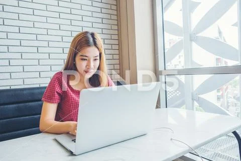 Asian girl working at a coffee shop with a laptop.female freelancer connect.. Stock Photos