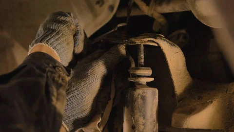 Asian in gloves and work clothes is repairing a spare part of a car in a garage Video stock 129831671