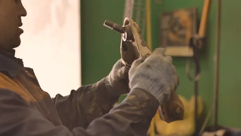 Asian in gloves and work clothes is repairing a spare part of a car in a garage Video stock 129832668