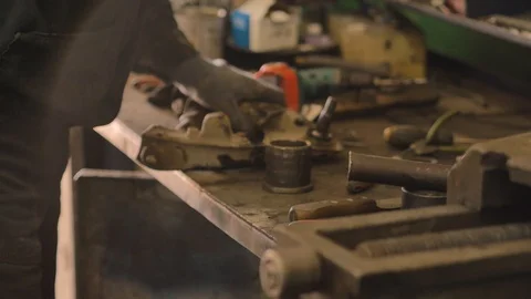 Asian in gloves and work clothes is repairing a spare part of a car in a garage Video stock 129832867