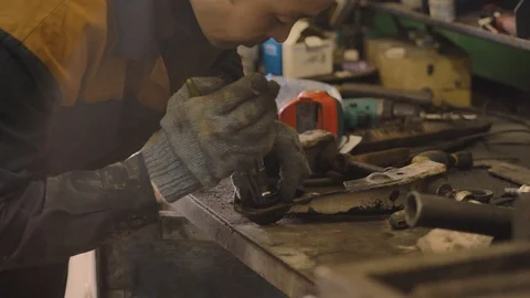 Asian in gloves and work clothes is repairing a spare part of a car in a garage Video stock 129833827