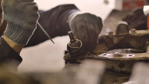 Asian in gloves and work clothes is repairing a spare part of a car in a garage Video stock 129834310