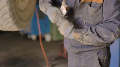 Asian in gloves and work clothes is repairing a spare part of a car in a garage Stock Footage 129840133