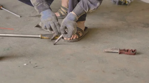 Asian in gloves and work clothes is repairing a spare part of a car in a garage Stock Footage 129840184