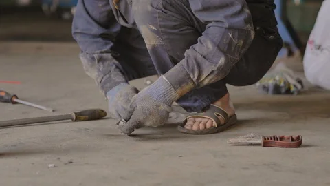 Asian in gloves and work clothes is repairing a spare part of a car in a garage Stock Footage 129840327