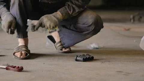 Asian in gloves and work clothes is repairing a spare part of a car in a garage Stock Footage 129840863