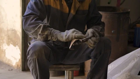 Asian in gloves and work clothes is repairing a spare part of a car in a garage Stock Footage 129842145