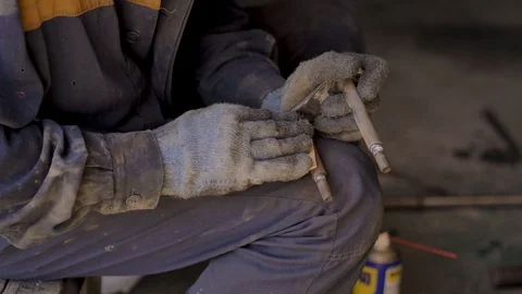 Asian in gloves and work clothes is repairing a spare part of a car in a garage Stock Footage 129842375