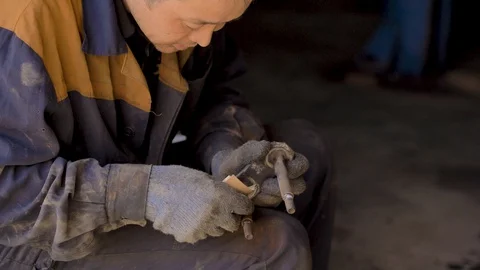 Asian in gloves and work clothes is repairing a spare part of a car in a garage Stock Footage 129842535