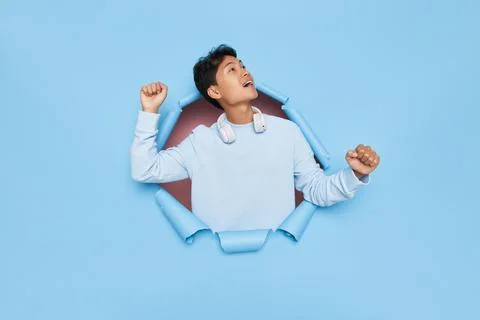 Asian guy model standing in the middle of blue background with fistss up in Foto stock