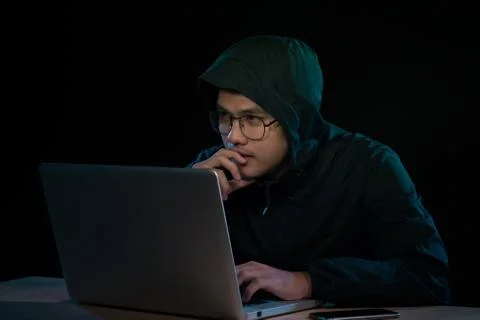 Asian hacker hacking computer network with laptop in dark. Cyber security con Stock Photos