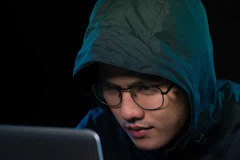 Asian hacker hacking computer network with laptop in dark. Cyber security con Stock Photos