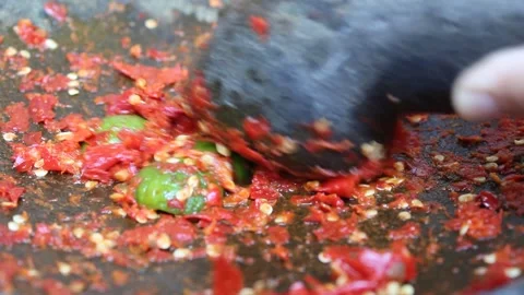 An asian hand pounding red chili and lime with stone mortar and pestle Stock Footage 294635008