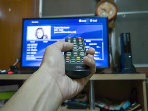 Asian hands use a remote control to connect a TV screen. or monitor Stock Photos