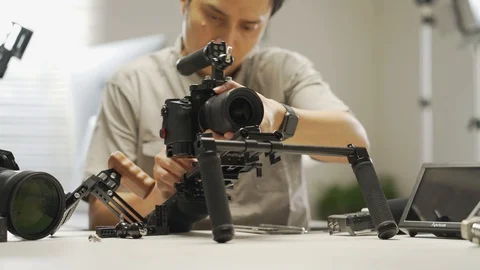 An Asian handsome man is installing a camera rig and fastening it Stock Footage 128407057
