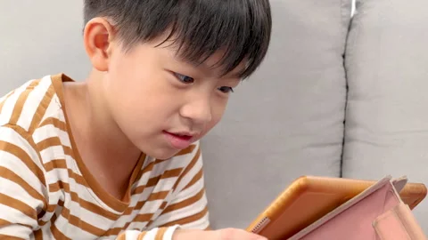 Asian happy boy lying down on couch play game with tablet computer, with fu.. Stock Footage 249581700